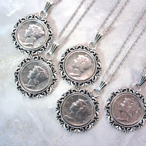 May include: Five silver necklaces with a silver coin pendant featuring a profile of a woman. Each necklace has a different length.