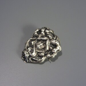 Pode incluir: Um broche de prata com um design floral. O broche &eacute; feito de prata e tem um padr&atilde;o floral detalhado. O broche &eacute; uma pe&ccedil;a vintage e est&aacute; em bom estado.