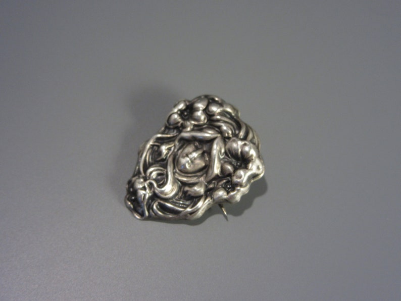 Pode incluir: Um broche de prata com um design floral. O broche &eacute; feito de prata e tem um padr&atilde;o floral detalhado. O broche &eacute; uma pe&ccedil;a vintage e est&aacute; em bom estado.