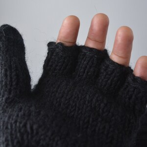 May include: Dark gray fingerless gloves, knitted with a textured stitch. The gloves are made of a soft, warm material, perfect for cold weather. The open fingertips allow for dexterity while keeping hands warm. A cozy accessory for fall and winter.