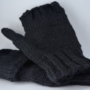 May include: A pair of dark gray knitted mittens. The mittens are made of a thick, textured yarn and have a ribbed cuff. The thumb and fingers are clearly defined, suggesting a comfortable fit. The mittens are likely handmade.