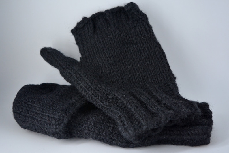 May include: A pair of dark gray knitted mittens. The mittens are made of a thick, textured yarn and have a ribbed cuff. The thumb and fingers are clearly defined, suggesting a comfortable fit. The mittens are likely handmade.