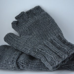 May include: A pair of gray knitted fingerless gloves. The gloves are made of a soft, textured yarn and feature a ribbed cuff and a simple knit stitch pattern. The gloves are designed to keep hands warm while leaving fingers free.