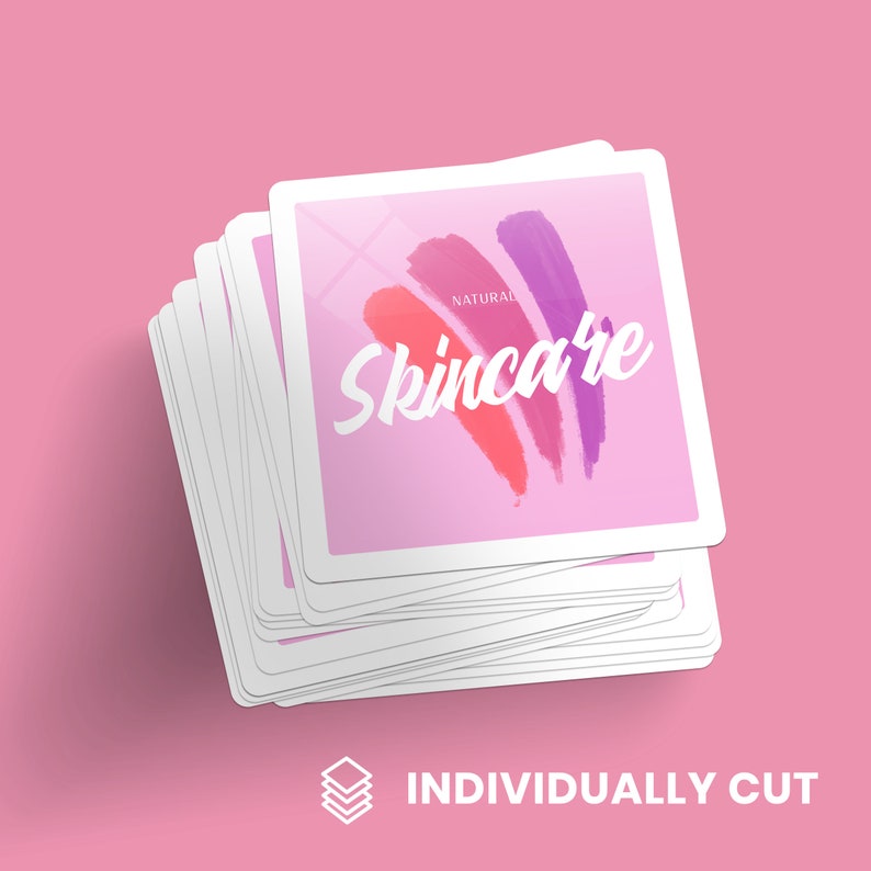 May include: A stack of individually cut square stickers with a pink background and white text that says "NATURAL Skincare". The stickers feature a design of three colorful brushstrokes in shades of pink, red, and purple.