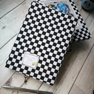 May include: Two black and white checkered notebooks with a keyhole and a label that says "Honey Pot Dolls". The top notebook has a photo of a doll wearing a blue dress.