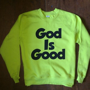 May include: A neon green sweatshirt with black text that reads "God Is Good".