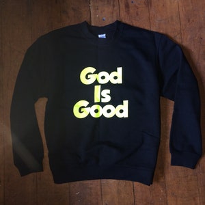 May include: Black sweatshirt with the words "God Is Good" printed in yellow.