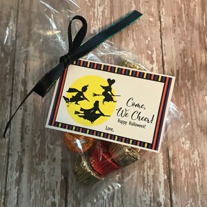 May include: A small clear plastic bag filled with chocolate candies tied with a black ribbon and a tag that says "Come, We Cheer! Happy Halloween!" with a picture of three witches flying on broomsticks in front of a yellow moon.