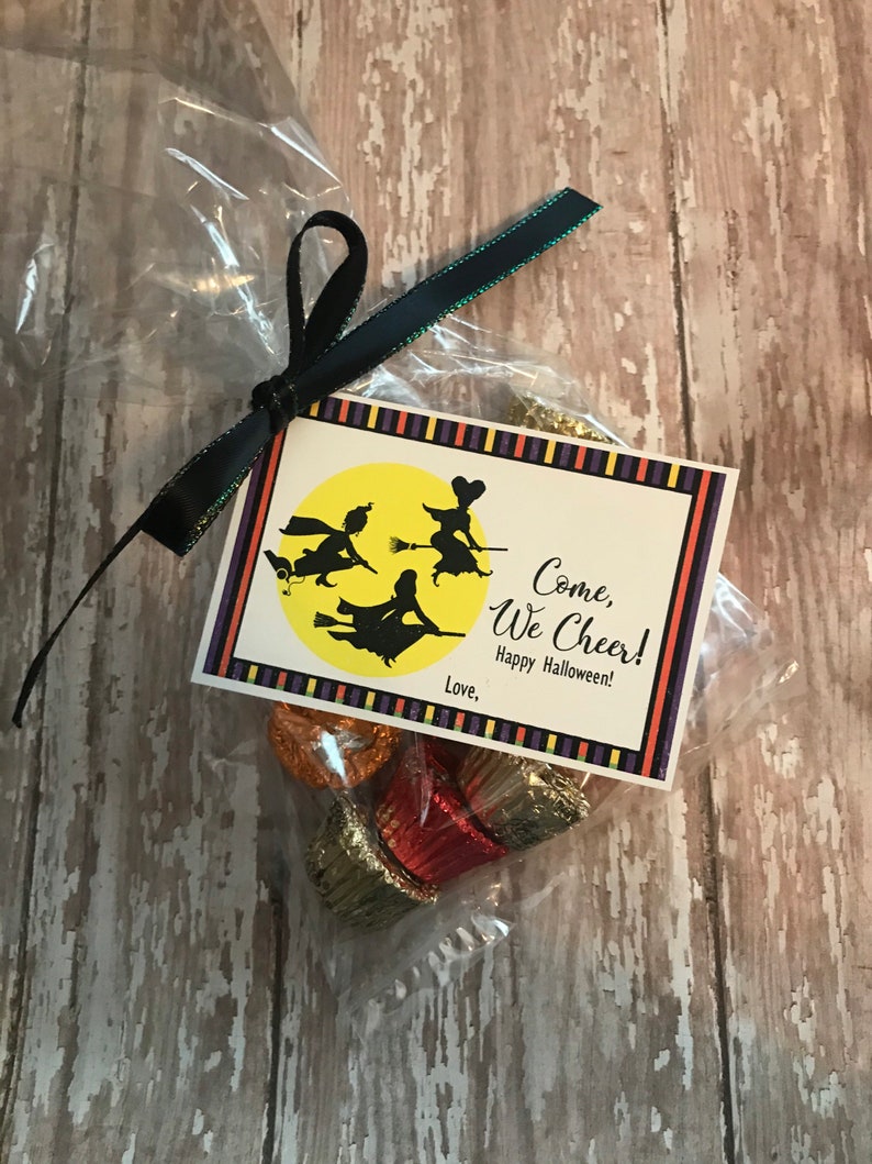 May include: A small clear plastic bag filled with chocolate candies tied with a black ribbon and a tag that says "Come, We Cheer! Happy Halloween!" with a picture of three witches flying on broomsticks in front of a yellow moon.