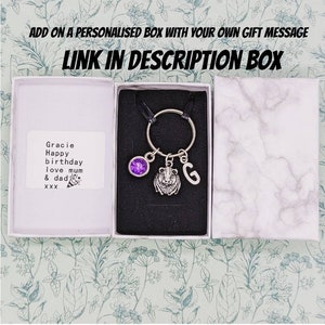 May include: A small gift box with a personalised message for Gracie. The box contains a keychain with a purple gem, a lion charm, and a letter G charm.