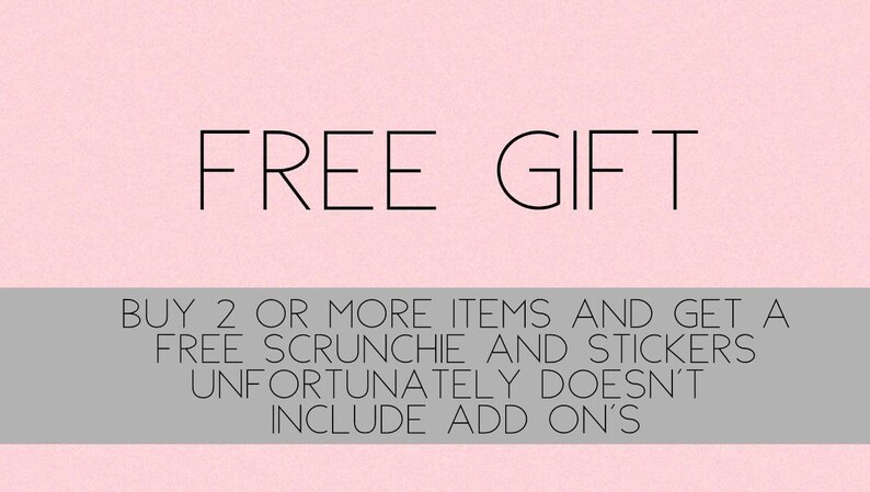 May include: Pink background with the text "FREE GIFT" in black. Below the text is a gray bar with the text "BUY 2 OR MORE ITEMS AND GET A FREE SCRUNCHIE AND STICKERS UNFORTUNATELY DOESN'T INCLUDE ADD ON'S".