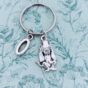 Puede incluir: Llavero de plata con un dije de letra O de plata y un dije de plata de un perro basset sentado.