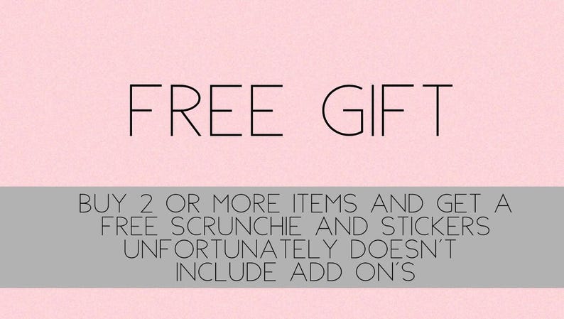 以下が含まれることがあります： ピンクの背景に黒い文字で「FREE GIFT」と書いてあります。テキストの下には、灰色の長方形があり、「BUY 2 OR MORE ITEMS AND GET A FREE SCRUNCHIE AND STICKERS UNFORTUNATELY DOESN'T INCLUDE ADD ON'S」と書いてあります。