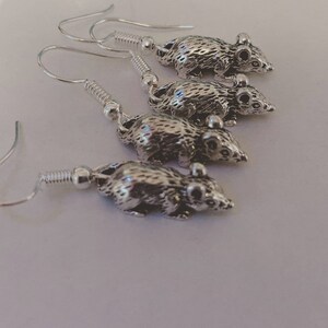 May include: Four pairs of silver rat earrings. Each earring features a detailed rat charm hanging from a silver hook.