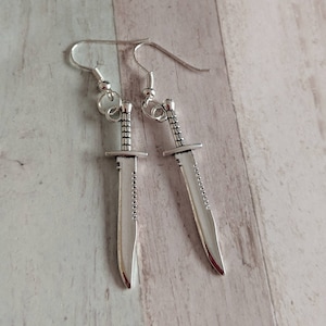 May include: A pair of silver earrings shaped like a knife.