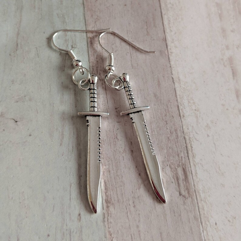 May include: A pair of silver earrings shaped like a knife.