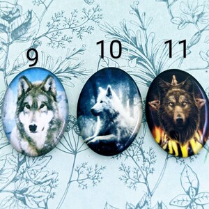 May include: Three round, oval-shaped buttons featuring wolf images. The first button depicts a grey wolf against a white background. The second button shows a white wolf against a dark blue background. The third button features a brown wolf against a dark background with a yellow and orange flame design.