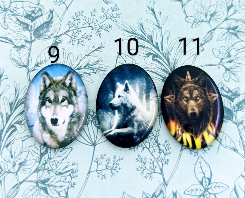 May include: Three round, oval-shaped buttons featuring wolf images. The first button depicts a grey wolf against a white background. The second button shows a white wolf against a dark blue background. The third button features a brown wolf against a dark background with a yellow and orange flame design.