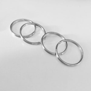 May include: Four silver key rings linked together. The rings are all the same size and are made of a smooth metal.