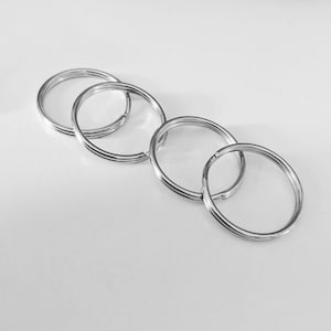 K&ouml;nnte beinhalten: Vier silberfarbene Schl&uuml;sselringe sind miteinander verbunden. Die Ringe bestehen aus gl&auml;nzendem Metall und haben ein schlichtes Design. Die Schl&uuml;sselringe sind diagonal auf einem wei&szlig;en Hintergrund angeordnet.