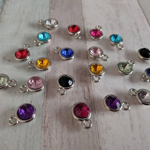 May include: Assortment of colorful rhinestone charms with silver settings. The charms are in various colors, including red, blue, green, pink, purple, orange, black, and white.