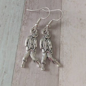 May include: A pair of silver earrings featuring a walking zombie figure. The earrings are made of metal and have a dangling design.