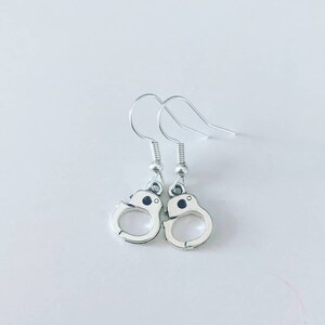 May include: A pair of silver dangle earrings shaped like handcuffs.