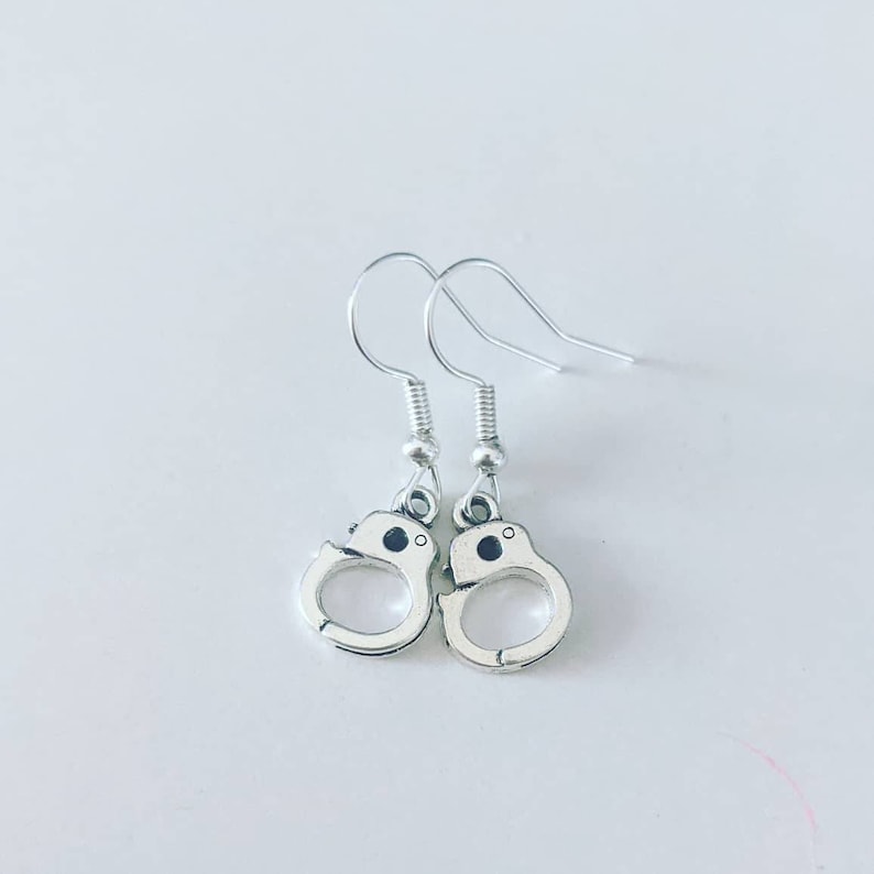 May include: A pair of silver dangle earrings shaped like handcuffs.