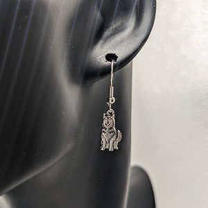 May include: Silver dangle earrings featuring a small husky dog charm.