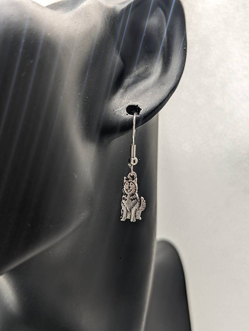 May include: Silver dangle earrings featuring a small husky dog charm.