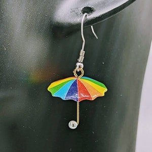Könnte beinhalten: Regenbogenfarbene Schirm-Ohrringe mit einem silbernen Haken und einem Perlenakzent.