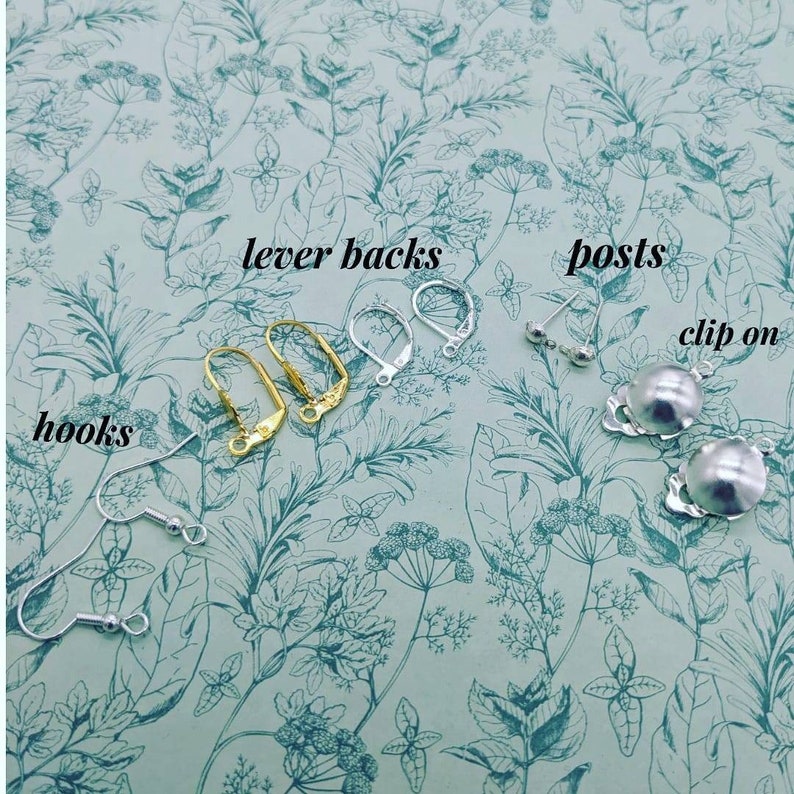 May include: A close-up of different earring findings, including lever backs, posts, hooks, and clip-on earrings. The findings are arranged in rows on a green floral background.