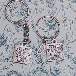 May include: Two silver keychains with a coffee cup design. The keychains have the text "Coffee is always a good idea" on them.