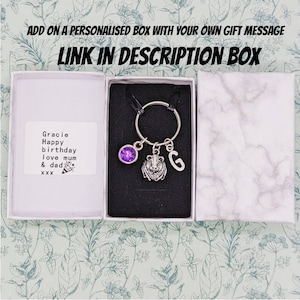 May include: A silver keychain with a guinea pig charm, a purple gem, and the letter "G" in an open gift box. The box contains a personalized message. Text on the image reads "ADD ON A PERSONALISED BOX WITH YOUR OWN GIFT MESSAGE LINK IN DESCRIPTION BOX."