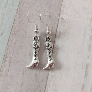 May include: Silver dangle earrings featuring a pair of detailed boot charms.