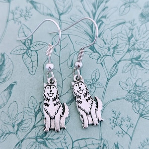 May include: A pair of silver dangle earrings featuring a wolf or husky design. The earrings have a silver hook and a silver spring.