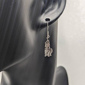 May include: Silver dangle earrings featuring a small, detailed husky dog charm.