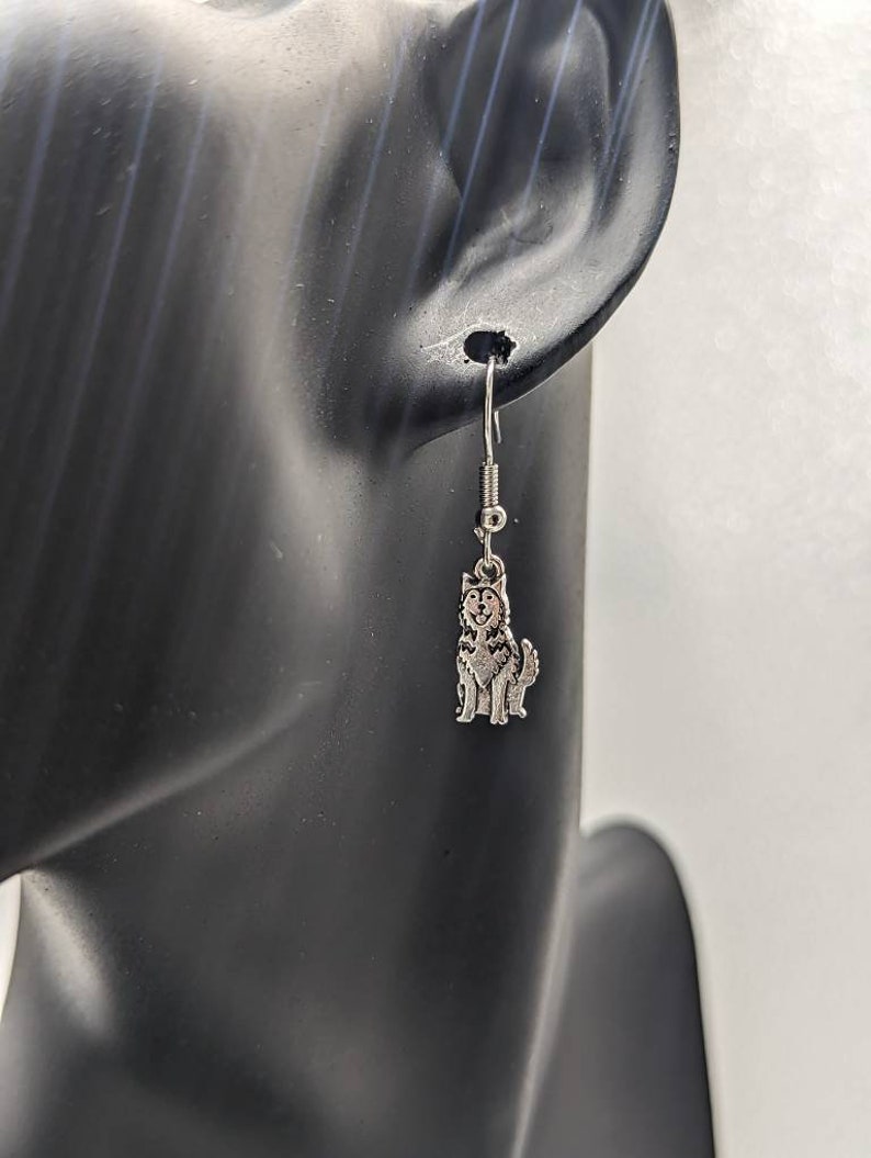 May include: Silver dangle earrings featuring a small, detailed husky dog charm.