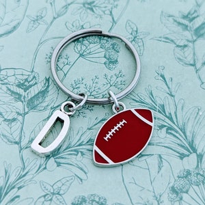 May include: Silver keyring with a letter D charm and a red and white football charm.