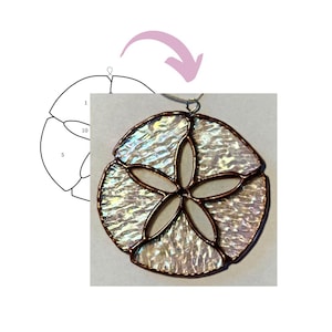 May include: A stained glass sand dollar pendant with iridescent glass and copper-coloured solder. The pendant has a five-petal star design in the centre and a circular shape. A diagram of the sand dollar's design is in the upper left corner.