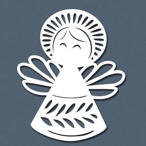 May include: White paper cut-out of an angel with a halo, wings, and a simple dress. The angel has a smiling face.