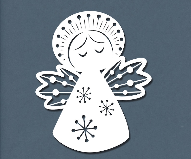 May include: White paper cut-out of an angel with a halo, closed eyes, and wings decorated with snowflakes. The angel is wearing a long gown with a snowflake pattern.