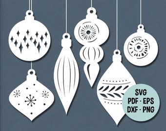 May include: Five white paper cut-out Christmas ornaments with different designs. The ornaments are hanging from strings against a blue background. The text "SVG PDF EPS DXF PNG" is in a light blue circle in the lower right corner.