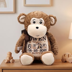 May include: A brown plush monkey toy with a cream-colored belly patch featuring embroidered text: OWEN Ryan, 6 POUNDS 10 OZ, 18 3/4 IN, 08-25-2025, 9:37 PM, and a small monkey graphic. The monkey has a dark brown ribbon tied around its neck.