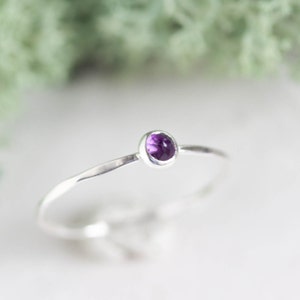 Peut inclure: Une délicate bague en argent avec une petite pierre d'améthyste de forme ovale.