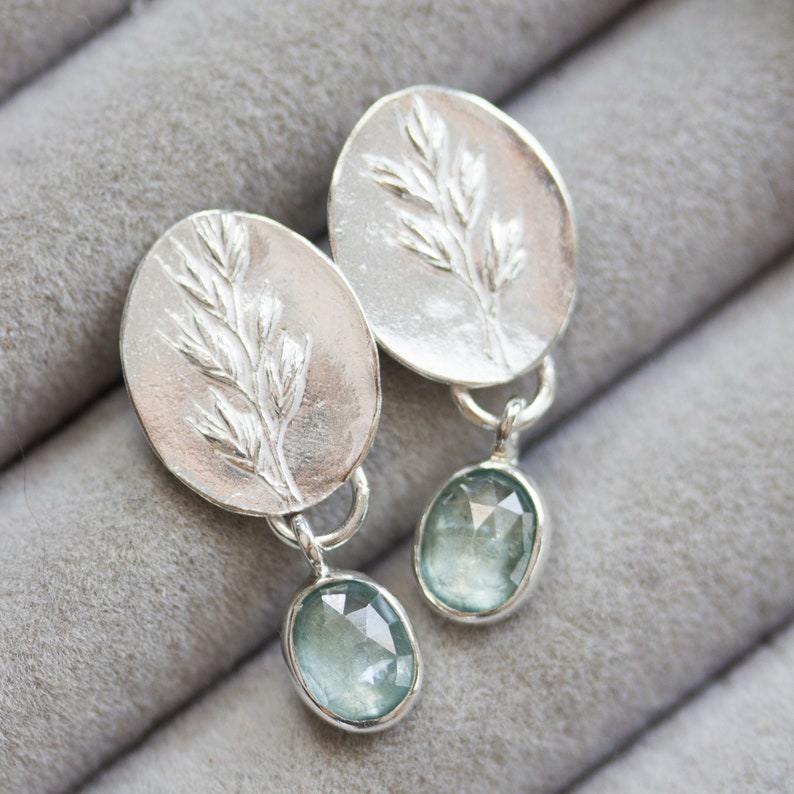 May include: Silver earrings with a delicate leaf design and light blue gemstone accents.