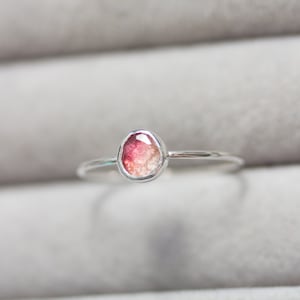 Puede incluir: Un anillo de plata con una piedra ovalada de color rosa y blanco.