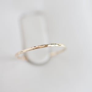 Może przedstawiać: Cienki, młotkowany złoty pierścionek.