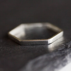 May include: A silver hexagonal ring with a flat, polished surface.