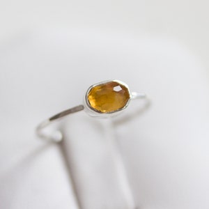 Puede incluir: Un anillo de plata con una piedra ovalada de color marrón claro.